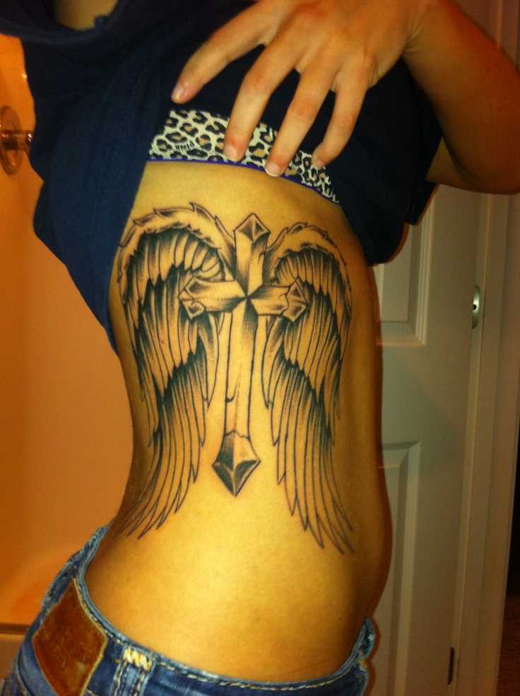 Tatuagem no lado da menina - asas e a cruz