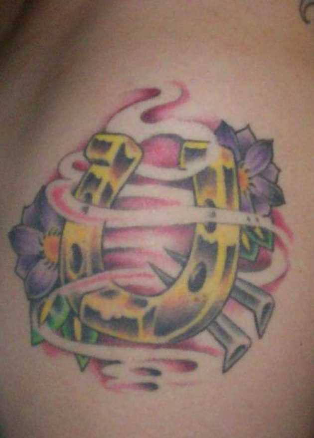 Tatuagem no lado da menina - ferradura e flores