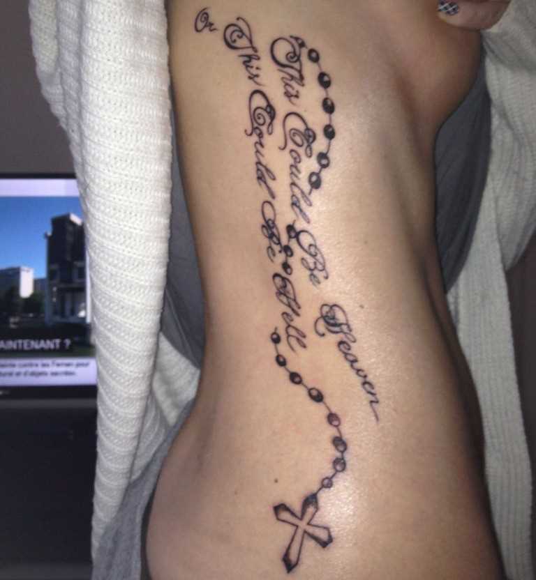 Tatuagem no lado da menina - um colar com uma cruz e a inscrição
