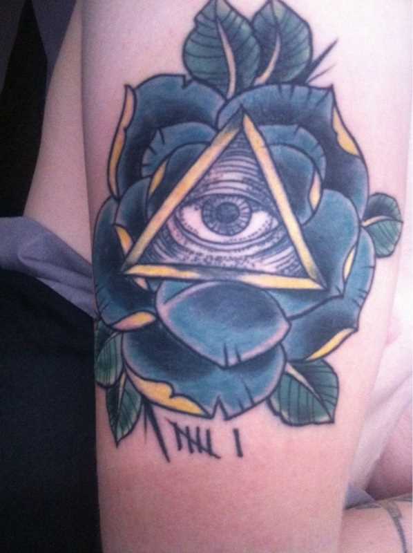 Tatuagem no ombro da menina - a pirâmide com o olho e a rosa