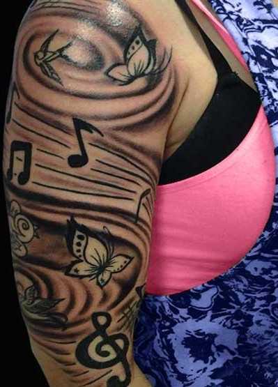 Tatuagem no ombro da menina - as notas da clave de sol e uma borboleta