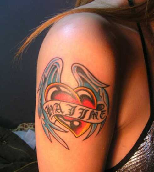 Tatuagem no ombro da menina - coração com asas e inscrição