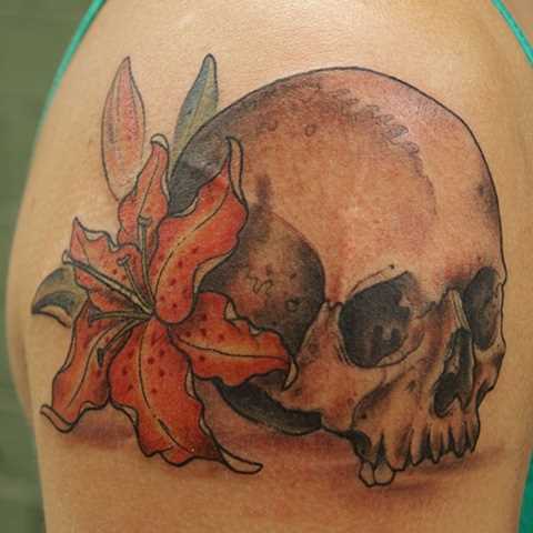 Tatuagem no ombro da menina em forma de lírio e o crânio
