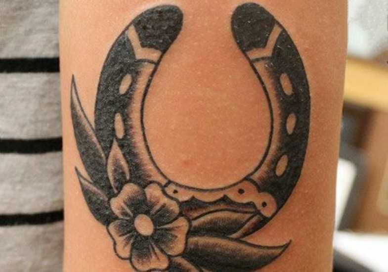 Tatuagem no ombro da menina - ferradura com flor