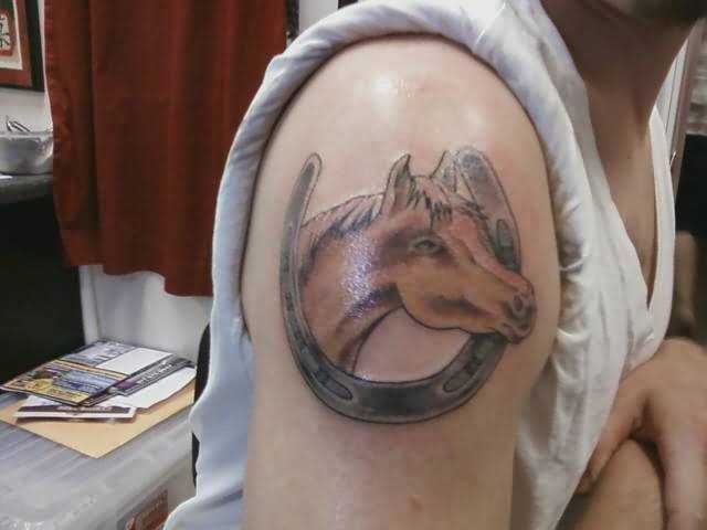Tatuagem no ombro da menina - ferradura e a cabeça de um cavalo