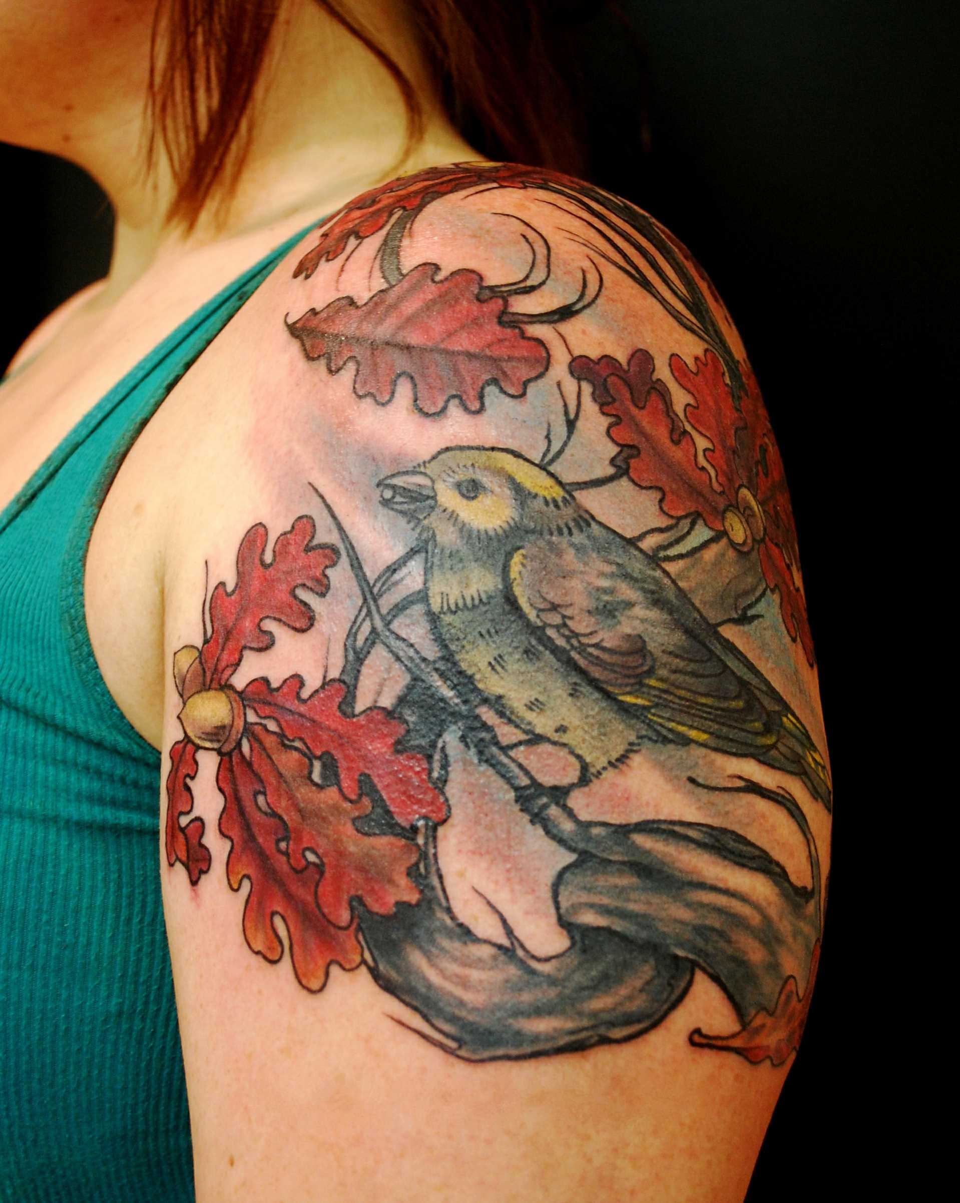 Tatuagem no ombro da menina - folhas e o pássaro