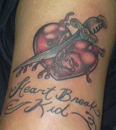 Tatuagem no ombro da menina - o coração, o punhal e a inscrição