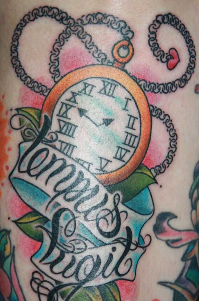 Tatuagem no ombro da menina - relógio de bolso e inscrição