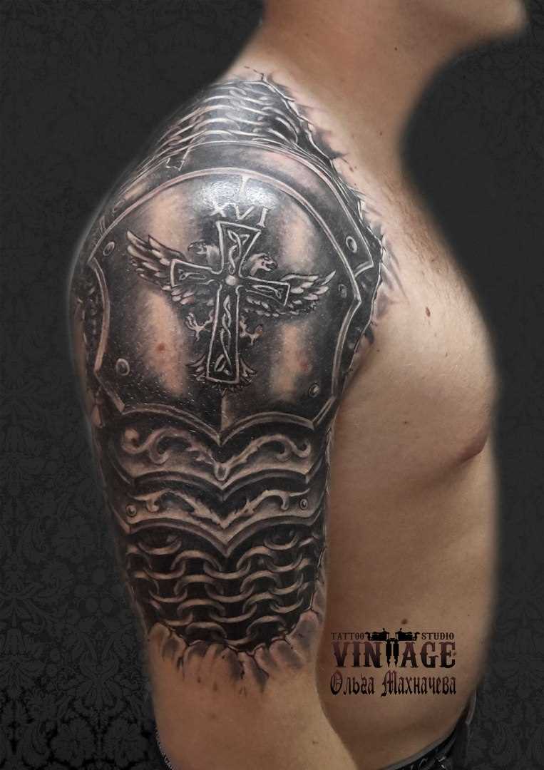 Tatuagem no ombro de um cara - a cruz e a armadura de