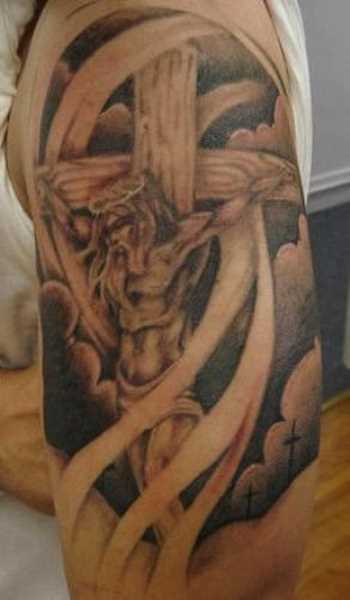 Tatuagem no ombro de um cara - a cruz e o crucificado Jesus