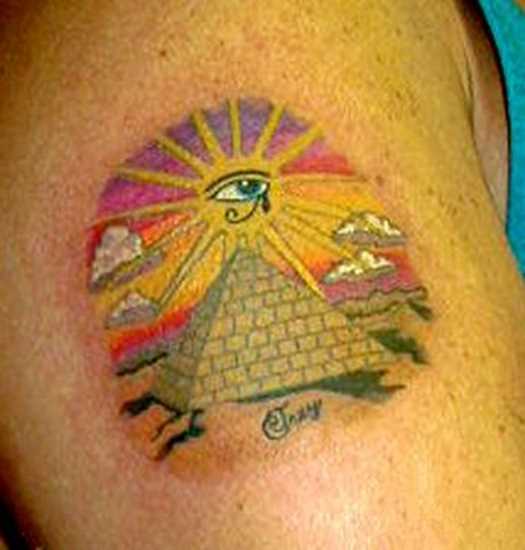 Tatuagem no ombro de um cara - a pirâmide com o olho e o sol