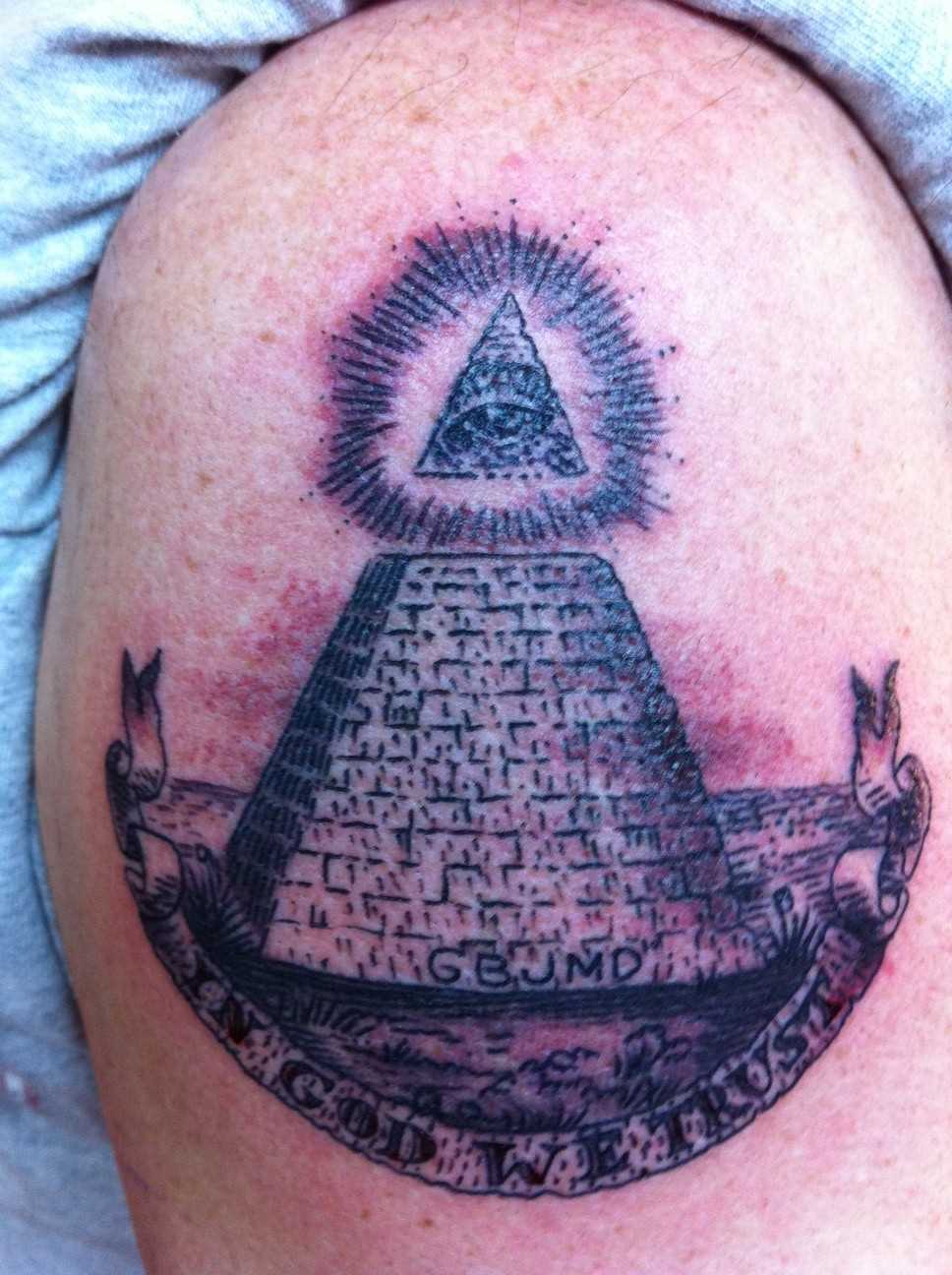 Tatuagem no ombro de um cara - a pirâmide com o olho