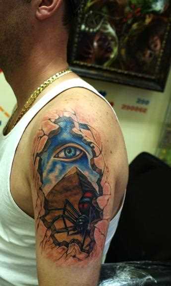 Tatuagem no ombro de um cara - a pirâmide, o olho e a aranha