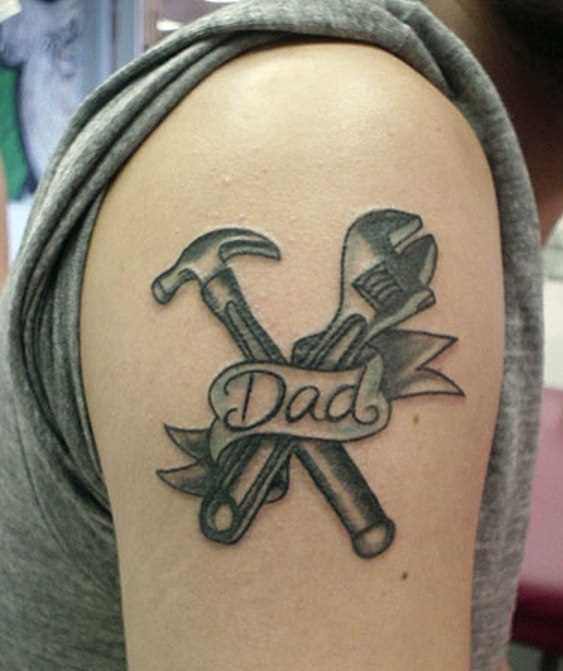 Tatuagem no ombro de um cara como martelo, chave e inscrições