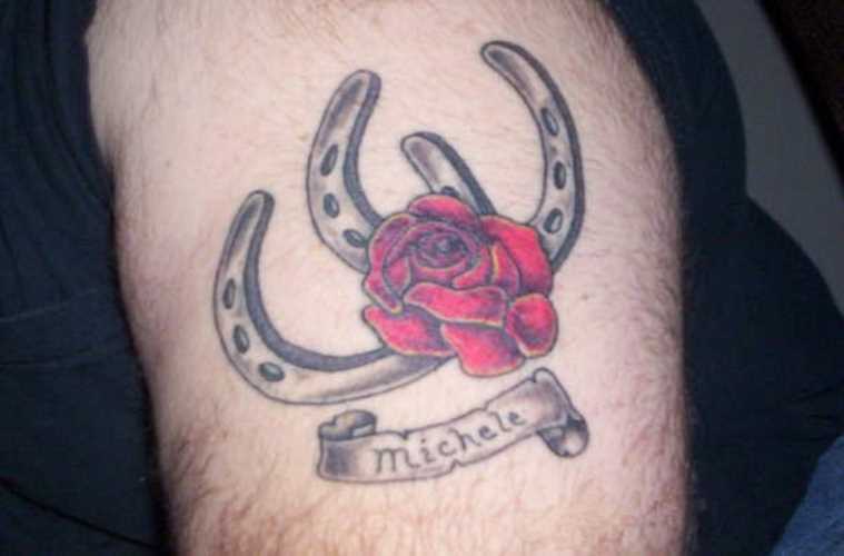 Tatuagem no ombro de um cara - duas ferraduras, rosa e inscrição