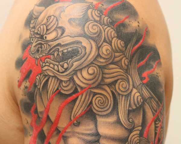 Tatuagem no ombro de um cara em forma de cão japonês