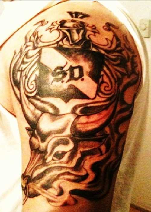 Tatuagem no ombro de um cara em forma de um touro e emblemas