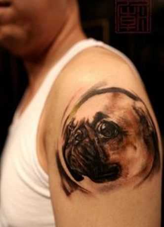 Tatuagem no ombro de um cara em forma de uma cabeça de cão
