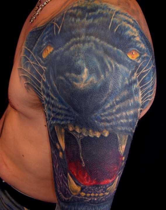 Tatuagem no ombro de um cara em forma de uma cabeça de pantera
