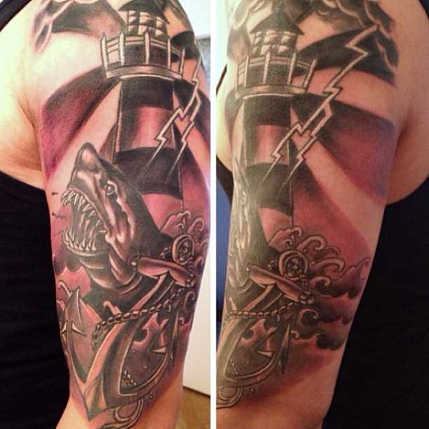 Tatuagem no ombro de um cara - farol, âncora, tubarão e relâmpago