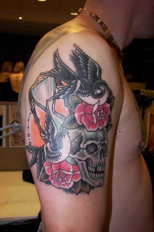 Tatuagem no ombro de um cara - relógio de areia, rosa, andorinhas e o crânio