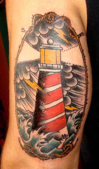 Tatuagem no ombro de um cara - um farol e um relâmpago