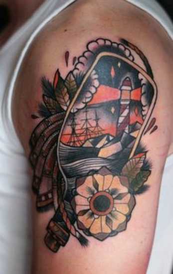 Tatuagem no ombro de um cara - um farol, um ofício e uma flor