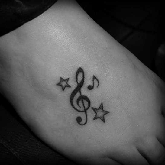 Tatuagem no pé da menina - nota, a clave de sol e estrelas