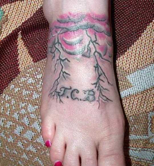 Tatuagem no pé da menina - relâmpago e uma inscrição em forma de iniciais