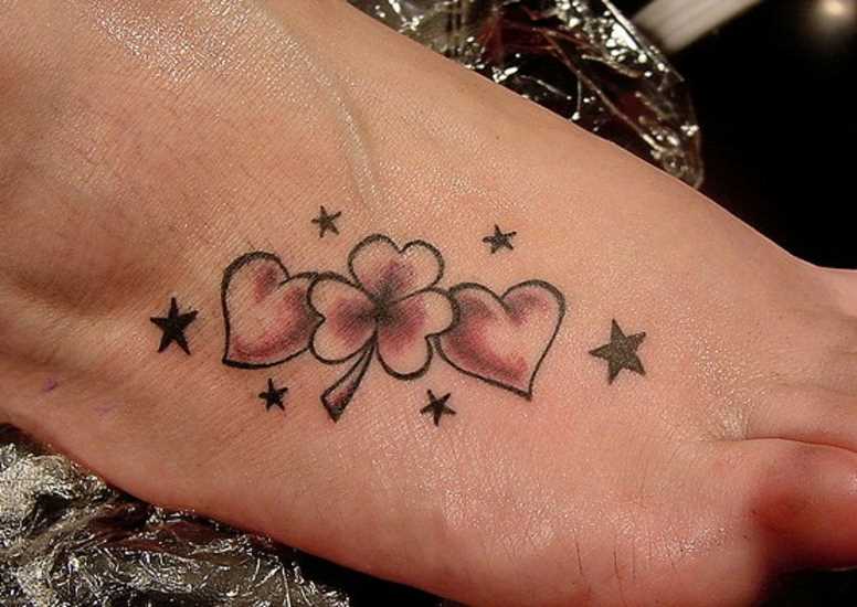 Tatuagem no pé de uma menina de coração, estrela e trevo