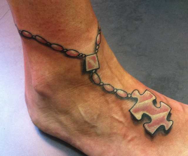 Tatuagem no pé de uma menina de quebra - cabeça em uma pulseira