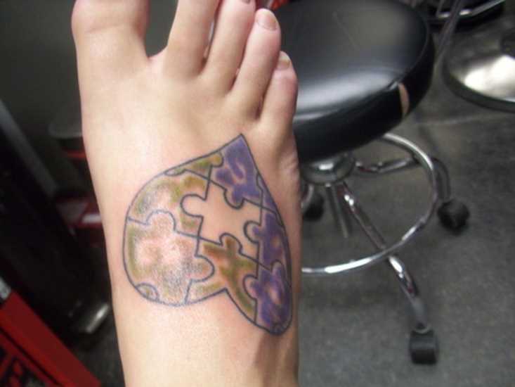 Tatuagem no pé de uma menina de quebra - cabeças em forma de coração