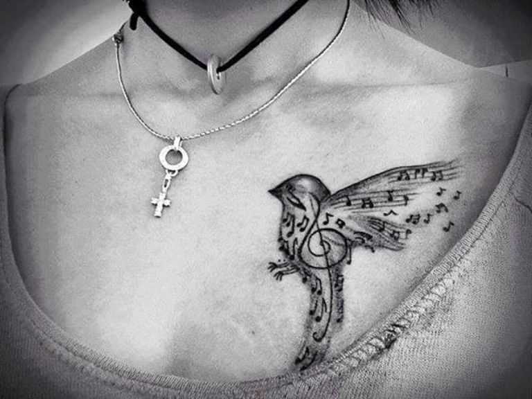 Tatuagem no peito da menina - as notas da clave de sol e o pássaro