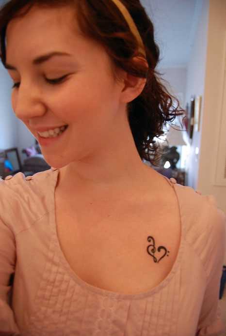 Tatuagem no peito da menina - clave de sol e o coração