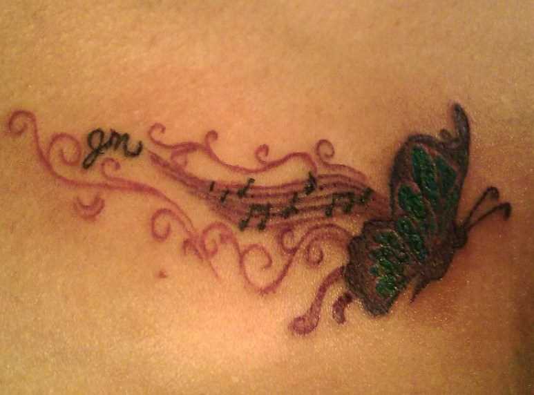 Tatuagem no peito da menina de notas e borboleta