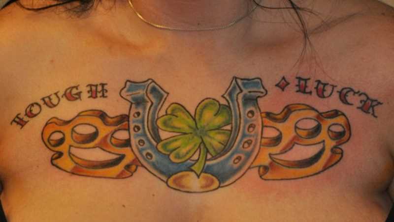 Tatuagem no peito da menina - ferradura, trevo e inscrição