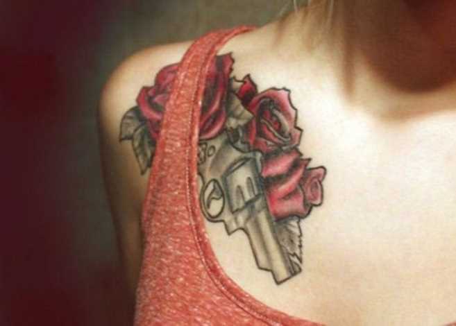 Tatuagem no peito da menina - uma pistola e rosas