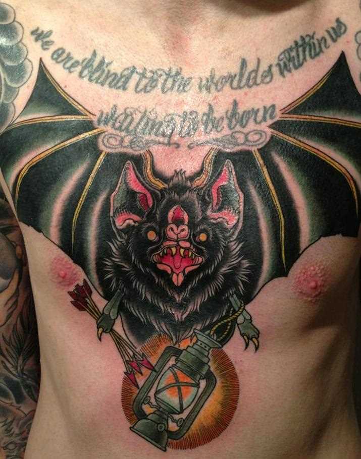 Tatuagem no peito do homem - morcego, uma lanterna e flecha