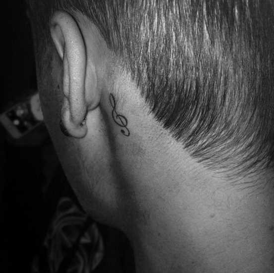 Tatuagem no pescoço de um cara atrás da orelha - clave de sol