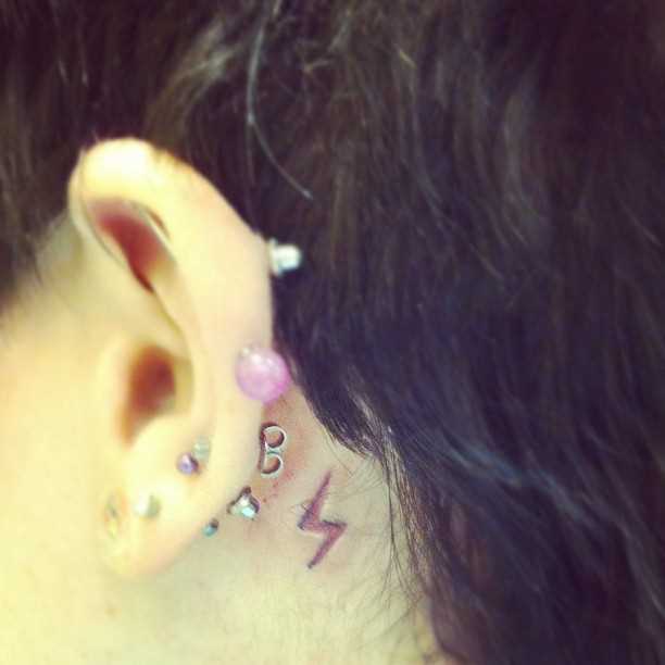 Tatuagem no pescoço de uma menina atrás da orelha - relâmpago