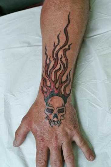 Tatuagem no pulso cara - de- fogo e o crânio