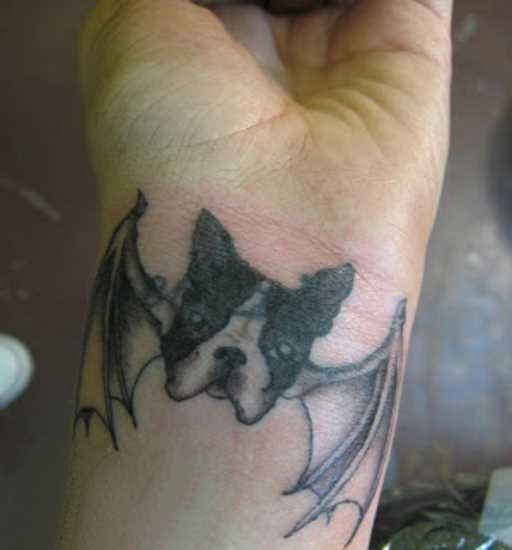 Tatuagem no pulso da menina - cão com asas de morcego