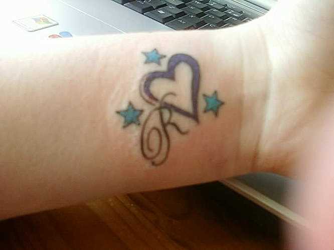 Tatuagem no pulso da menina, coração, estrela e letra