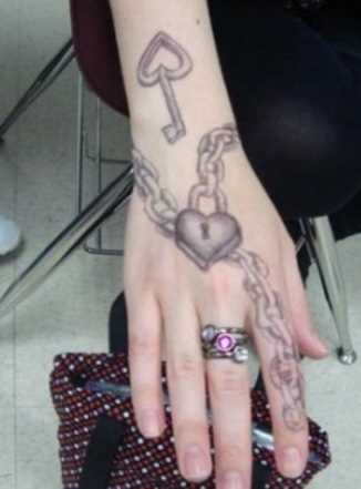 Tatuagem no pulso da menina - corrente com cadeado em forma de coração e uma chave