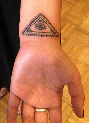 Tatuagem no pulso da menina - o triângulo e o olho