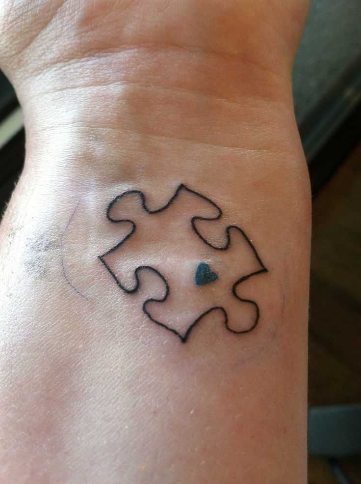 Tatuagem no pulso da menina - quebra-cabeça com um coração