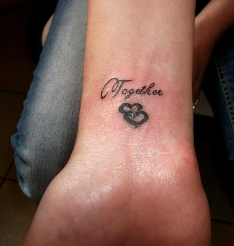 Tatuagem no pulso de uma menina de coração e inscrição
