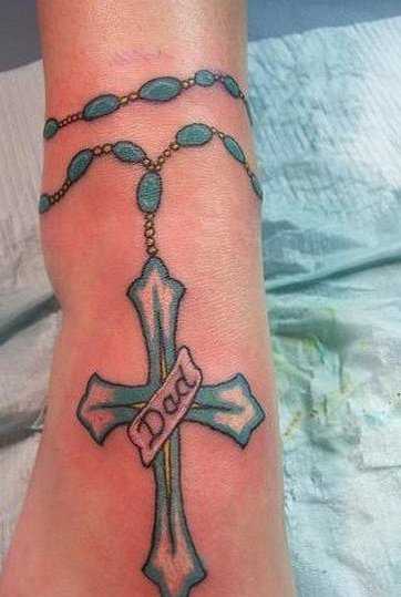 Tatuagem no tornozelo preto da menina - um colar com uma cruz e a inscrição