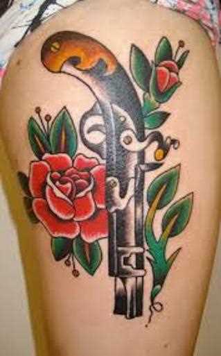 Tatuagem que a menina nos quadris em forma de pistola e de rosas