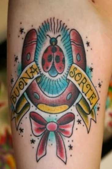 Tatuagem que tem no braço da menina - ferradura, inscrição, joaninha e borboleta